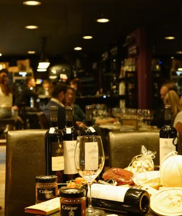 Warm Athens wine bar atmosphere with Greek wine bottles and wine glass at Cinque Wine & Deli